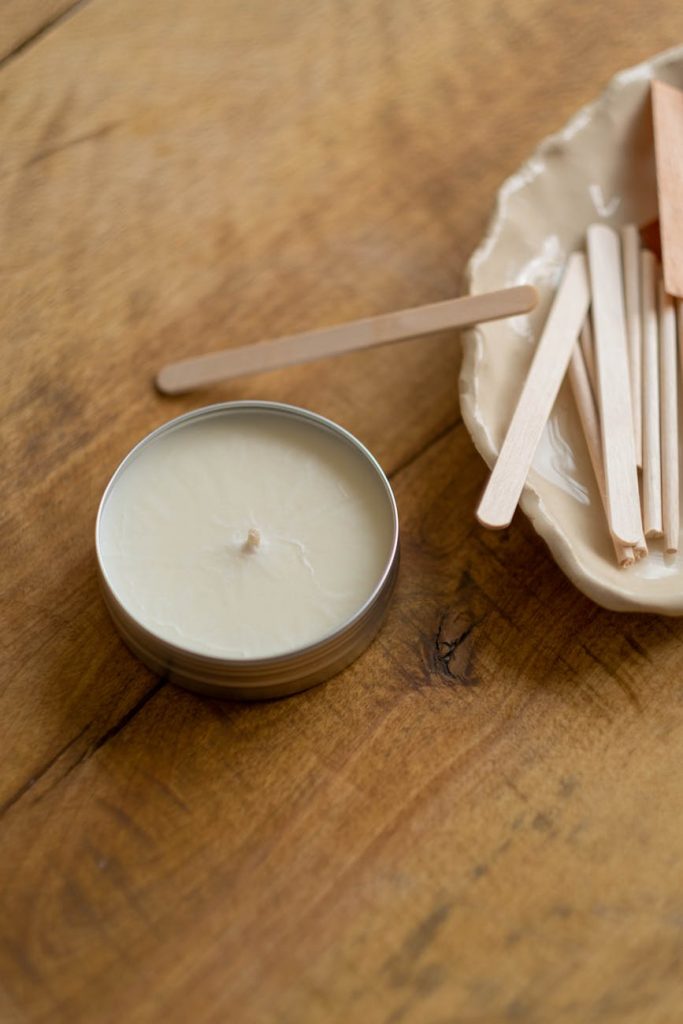 white candle near popsicle sticks